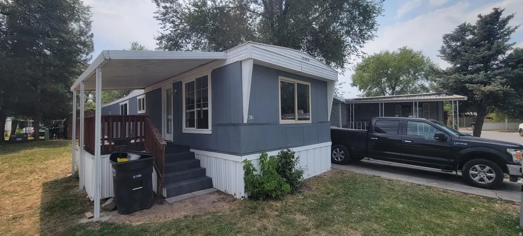 Manufactured home featuring a covered front porch, exterior steps, and a paved parking area
