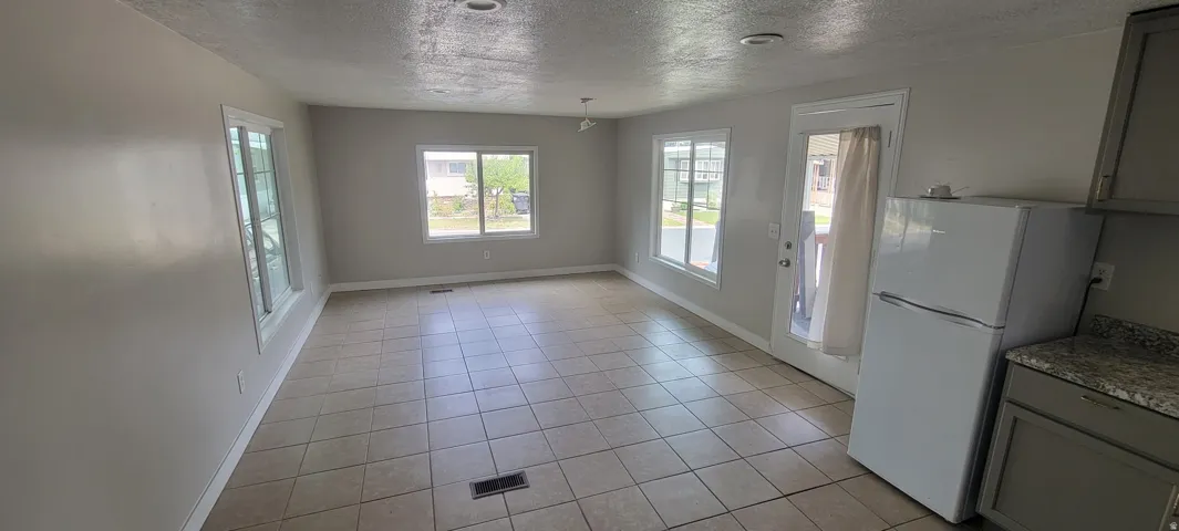 Open-concept living area featuring tile flooring, multiple windows, a rear exterior door, and recessed lighting
