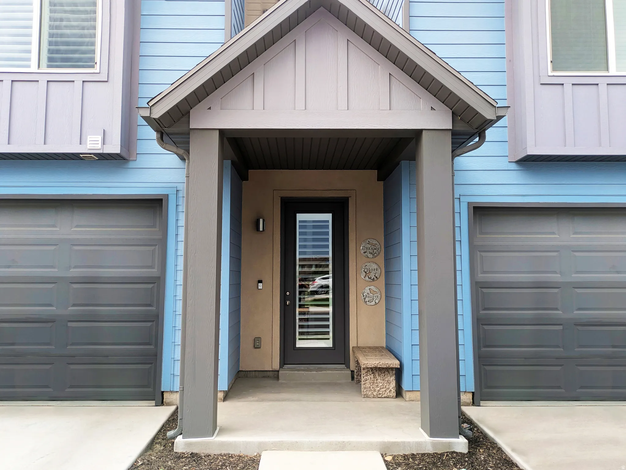 Covered entry with gray support columns and a full-light entry door