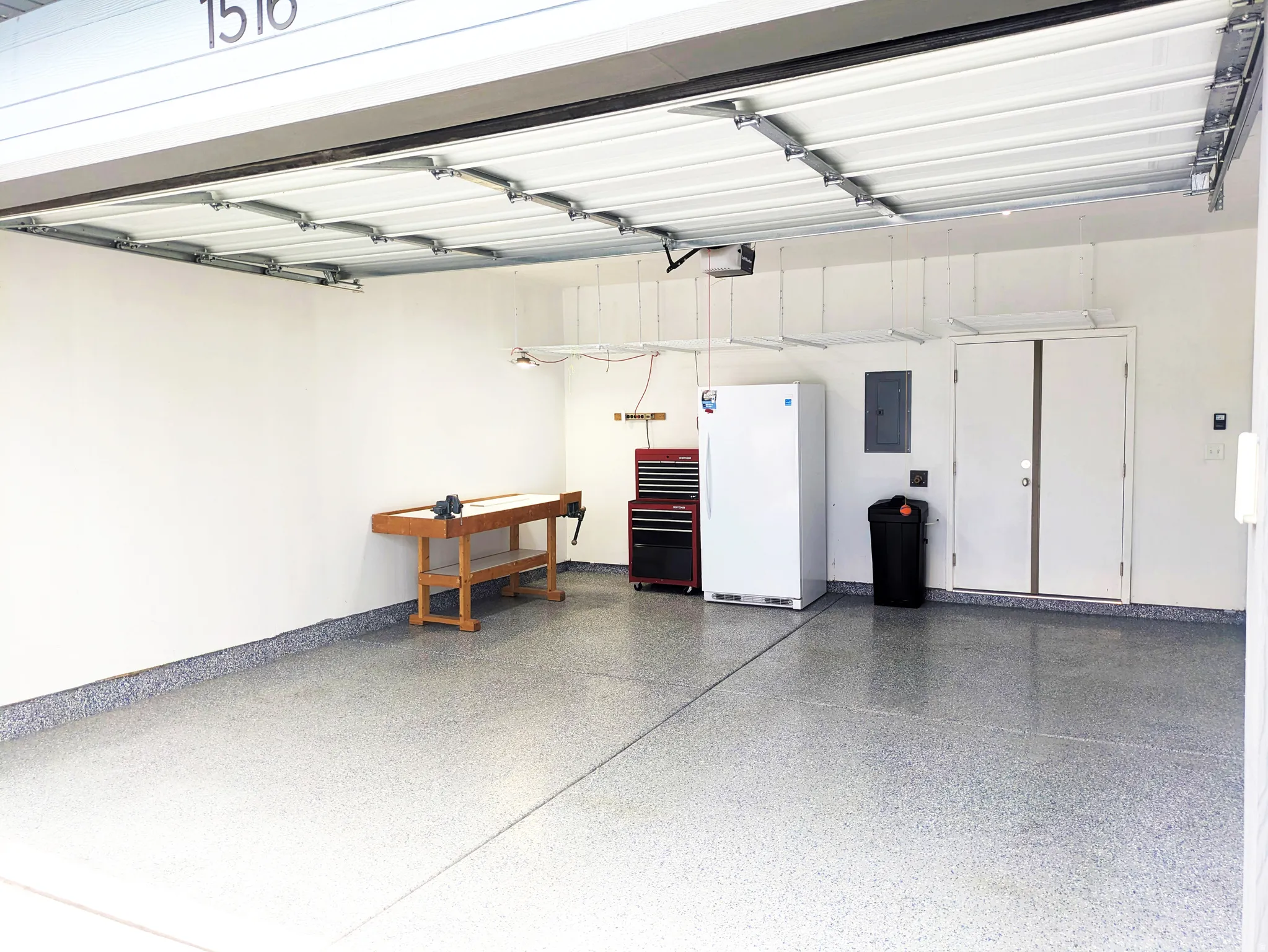 Two-car garage with a durable epoxy floor finish, overhead storage racks, and an internal access door