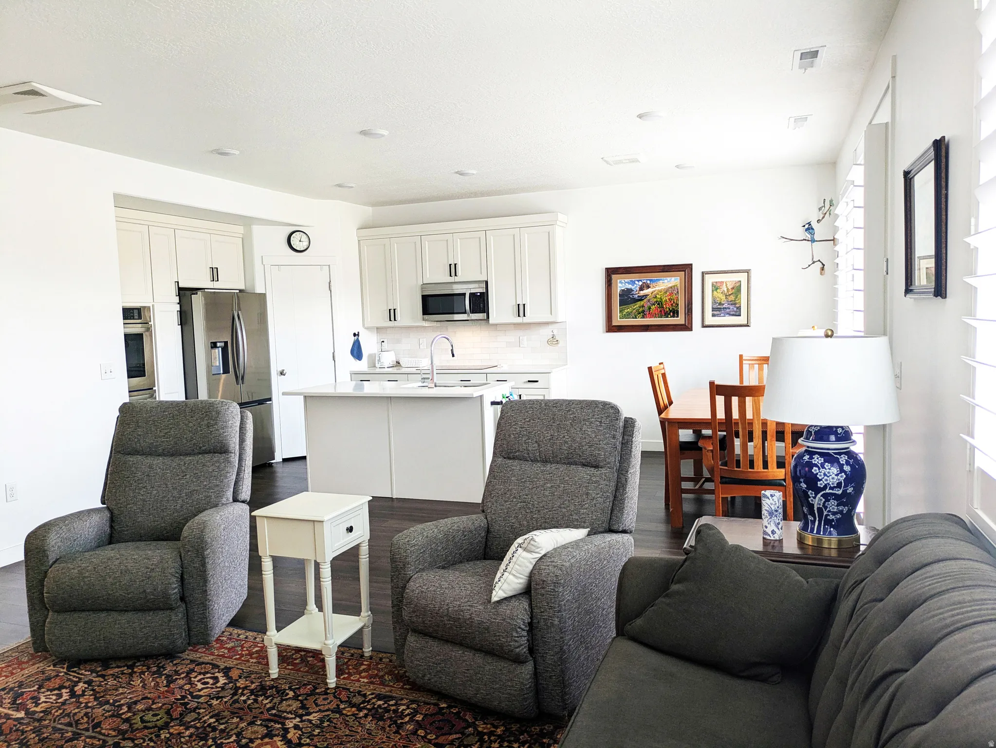 Open-concept living area with wood-finish flooring, recessed lighting, and white plantation shutters