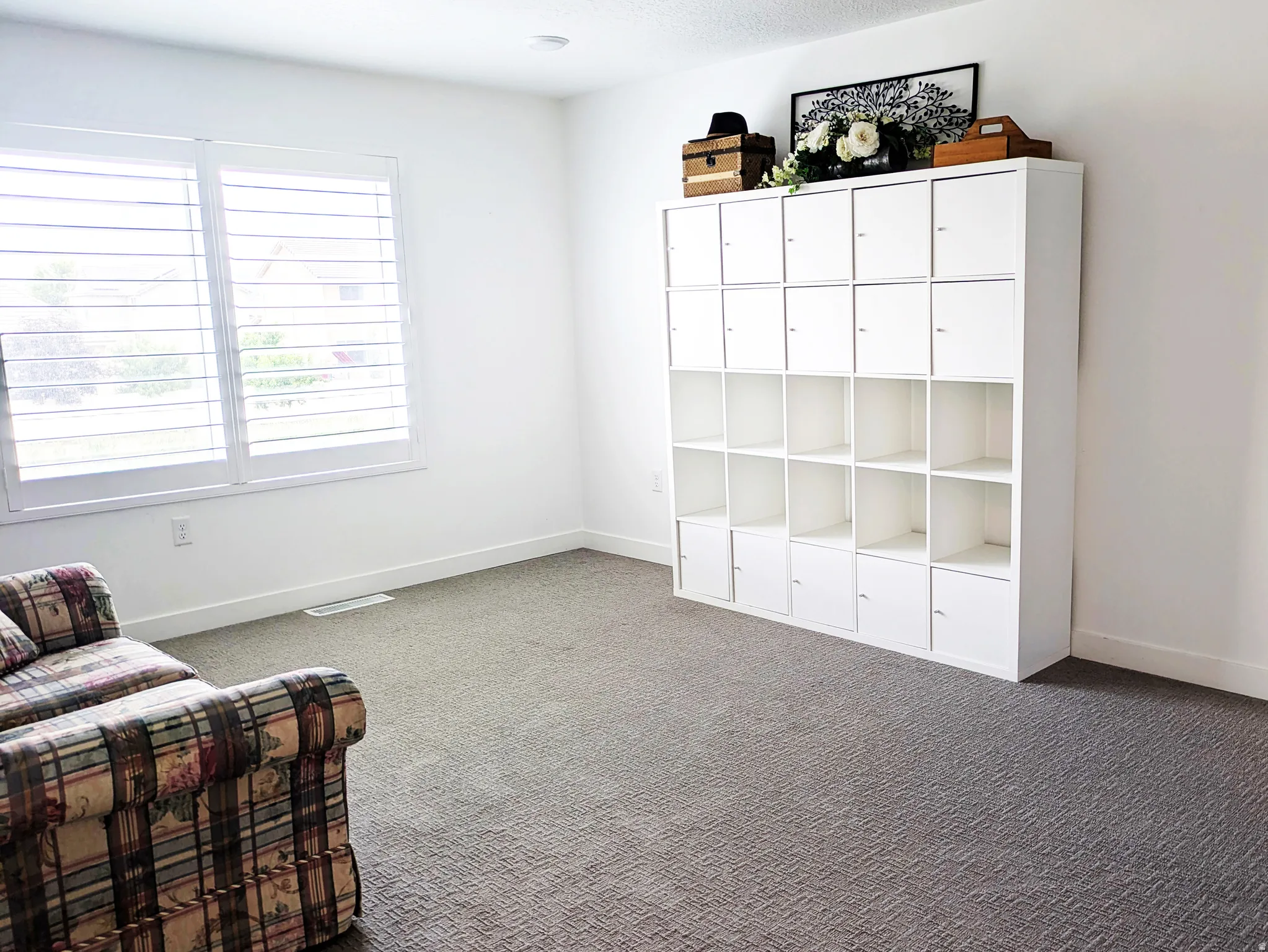 Recessed ceiling lighting, window with white plantation shutters, white walls, and gray patterned carpeting