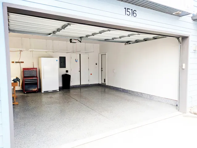 Attached garage with an overhead door, finished floor, and painted walls