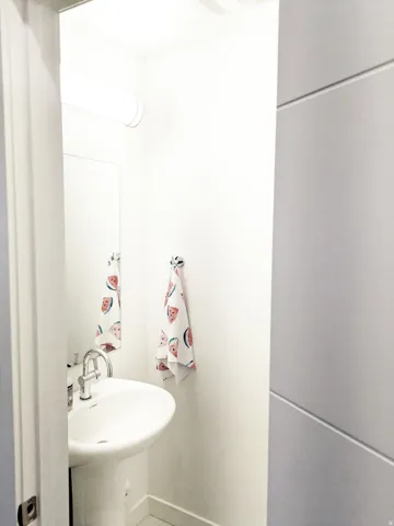 Pedestal sink with a chrome faucet, wall-mounted mirror, and overhead lighting