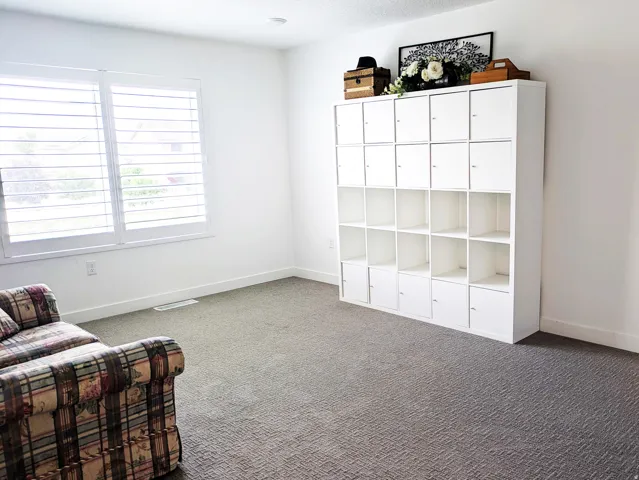 Recessed ceiling lighting, window with white plantation shutters, white walls, and gray patterned carpeting