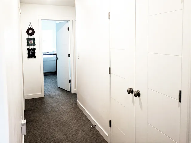 Hallway with textured carpeting and white walls