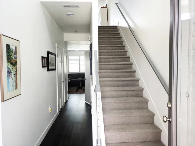 Hallway featuring dark wood-finish flooring, white walls, and multiple panel doors