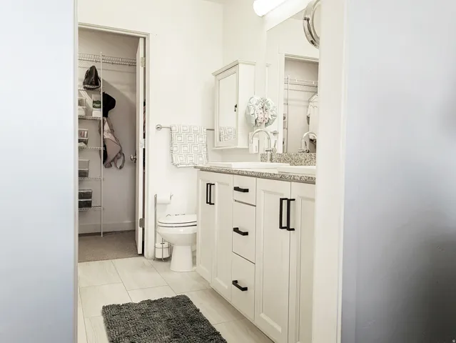 White vanity with black cabinet hardware, dual sinks, and a large vanity mirror