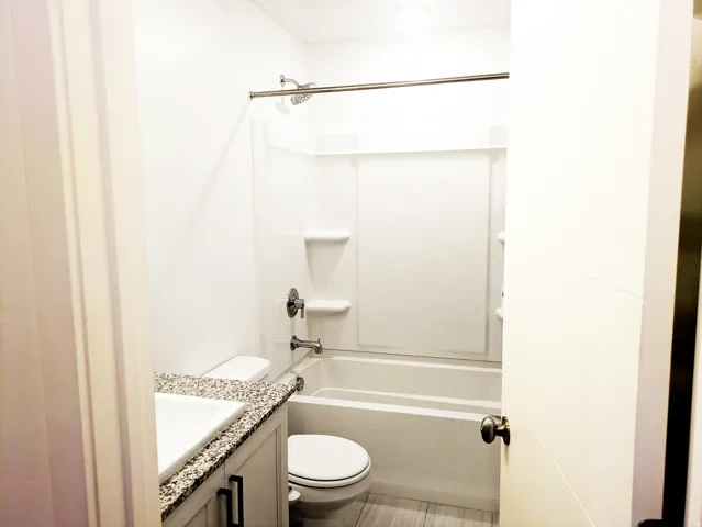 Full bathroom featuring a shower-over-tub combination, single vanity with a speckled countertop, and recessed lighting