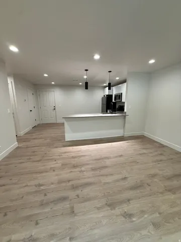 Open-concept living space with wood-finish flooring, recessed lighting, and a kitchen island with pendant lighting