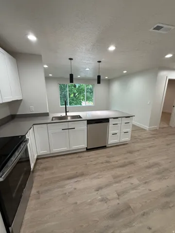 Kitchen featuring white shaker cabinetry, stainless steel appliances, recessed lighting, and wood-finish flooring