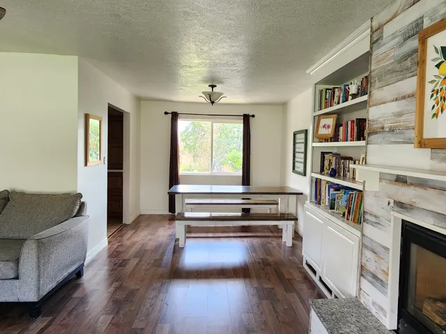 Wood-finish flooring throughout, integrated built-in shelving, and a decorative fireplace with a shiplap-style surround and stone hearth