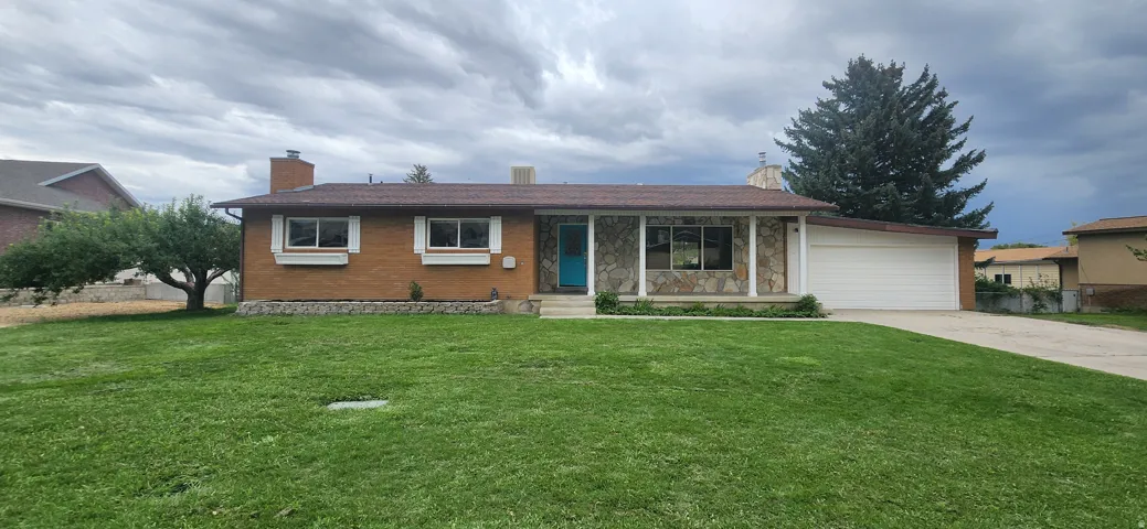 Brick and stone facade with a covered entry, an attached garage, and a concrete driveway