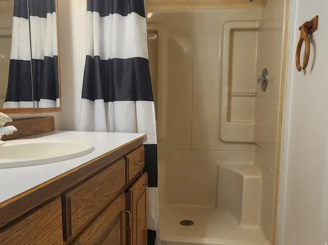 Vanity with wood-finish cabinetry, integrated sink, and overhead lighting