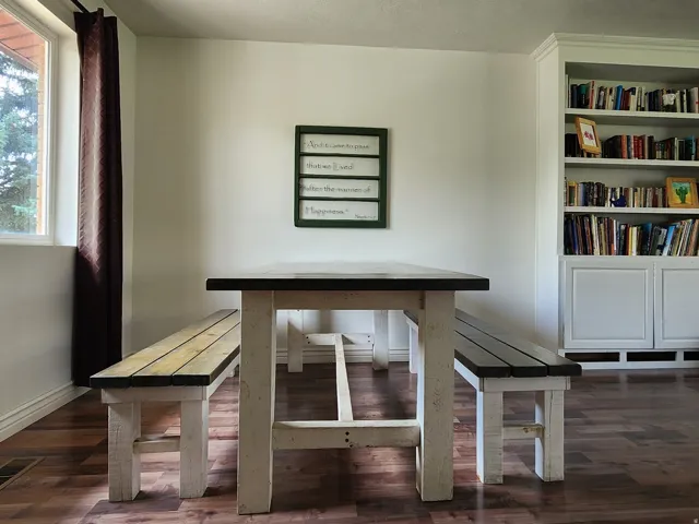 Bright, open study featuring hardwood flooring, large windows with natural light, built-in shelving with glass-front cabinetry, and a minimalist work surface with integrated storage
