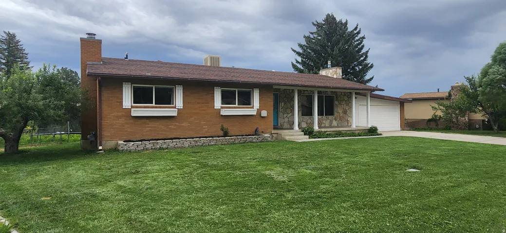 Brick exterior with stone facade accents, covered front entry, attached garage, and a well-maintained lawn