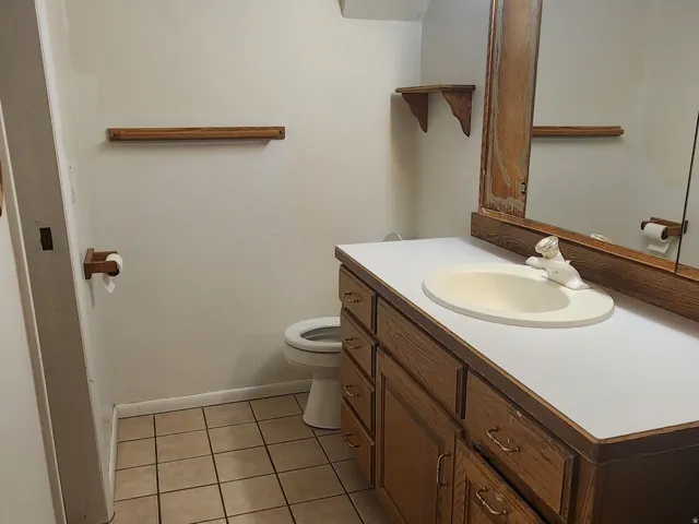 Vanity with wood-finish cabinetry, integrated sink, and countertop