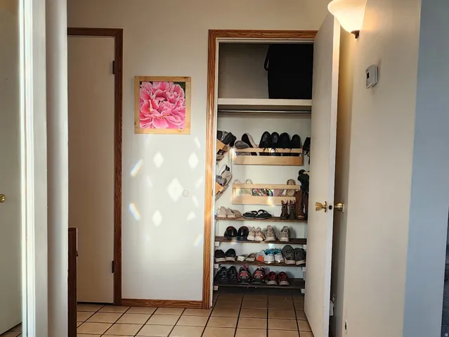 Tiled flooring throughout the entryway with wood trim accents and a built-in storage closet