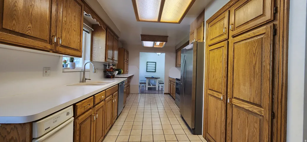 Kitchen featuring wood cabinetry, white countertops, stainless steel appliances, and a tile floor