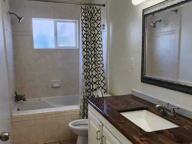 Bathroom featuring a white vanity with a wood-finish countertop, undermount sink, and tiled flooring