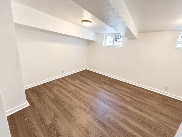 Spacious room featuring wood-finish flooring, white walls, and dual windows