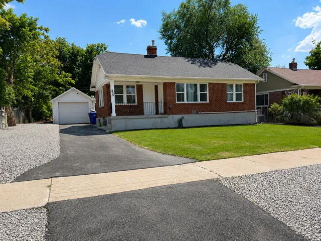 Brick exterior with white trim, a covered front porch, and an attached garage with an asphalt driveway