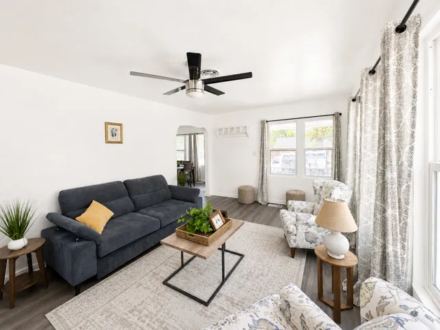 Spacious living area featuring wood-finish flooring, a contemporary ceiling fan, and an arched doorway