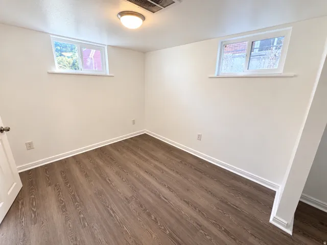 Wood-finish flooring, white walls, two windows, and a flush mount ceiling light