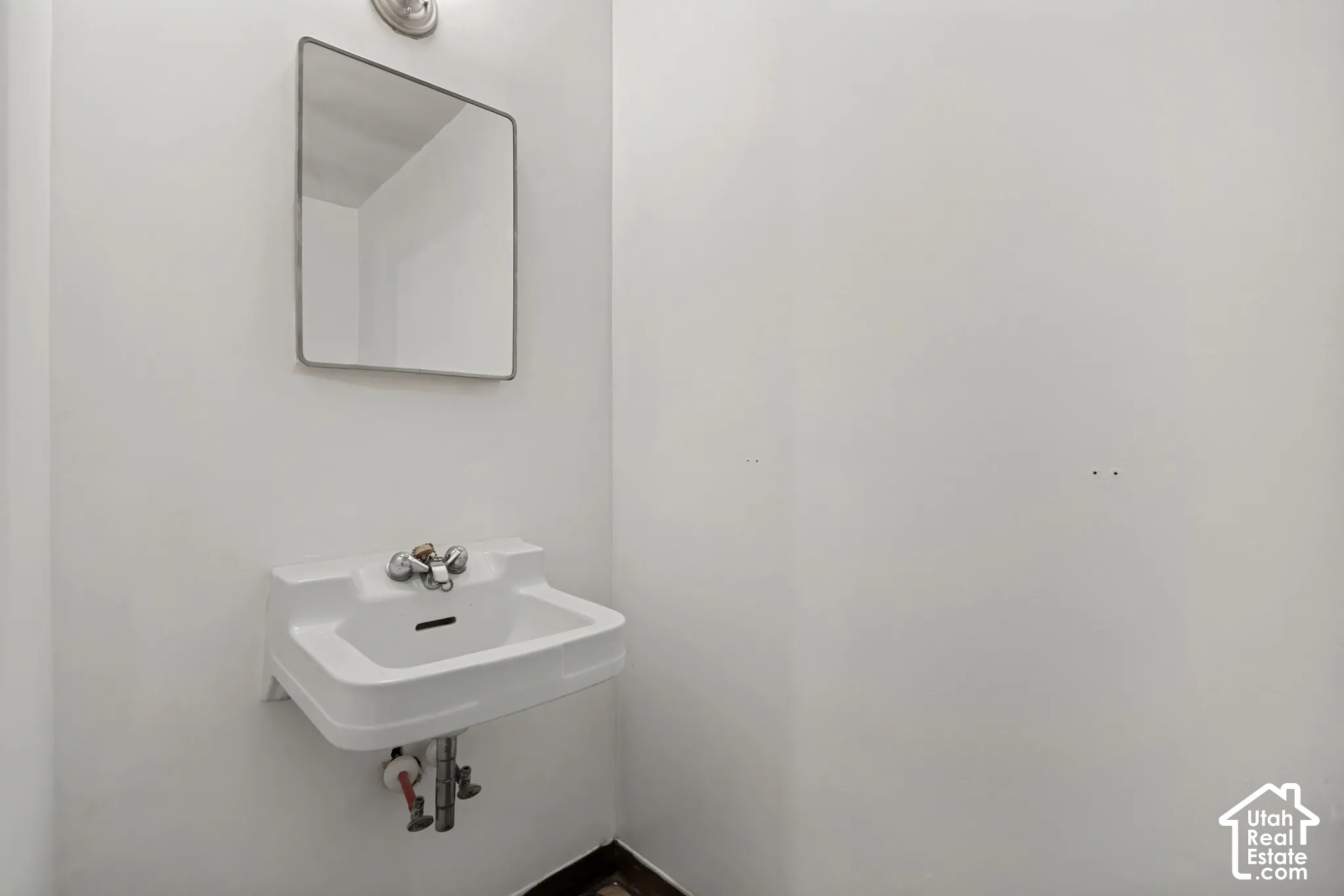 Wall-mounted sink with chrome-finish fixtures and an overhead rectangular mirror