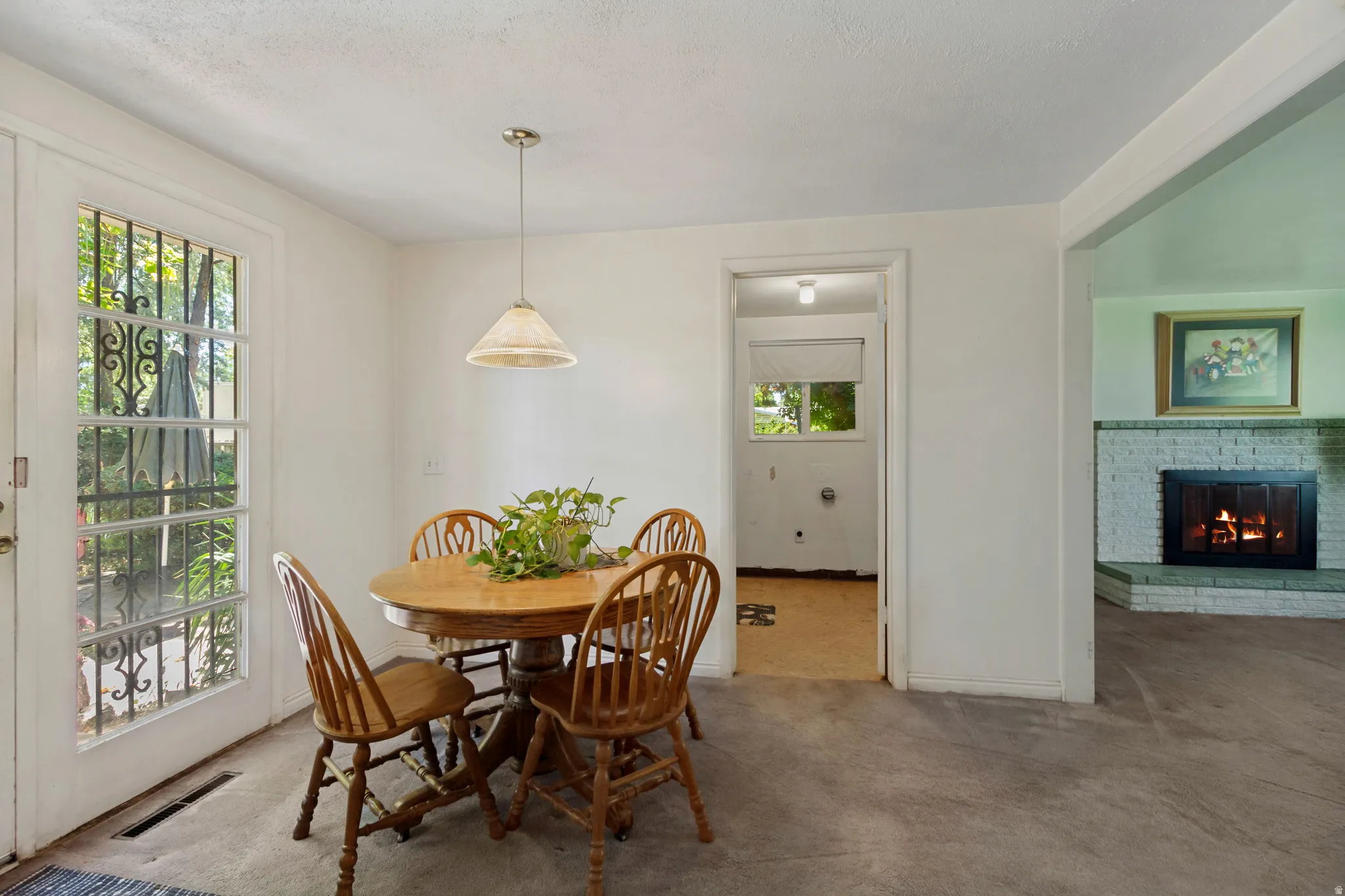 Open concept living space featuring a white brick fireplace, a glass-paned exterior door, and a pendant light fixture