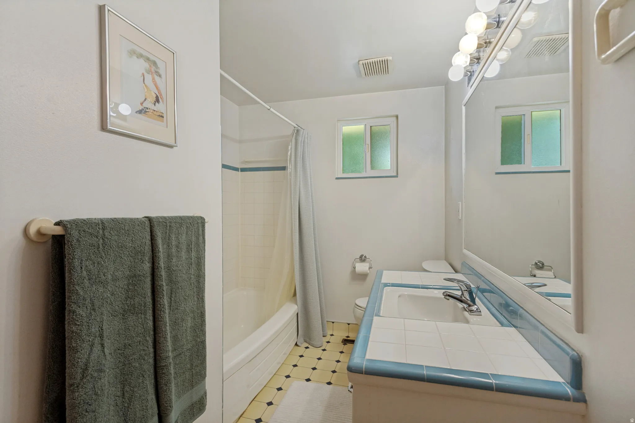 Bathroom with a single vanity, tiled countertop, integrated sink, and vanity lighting