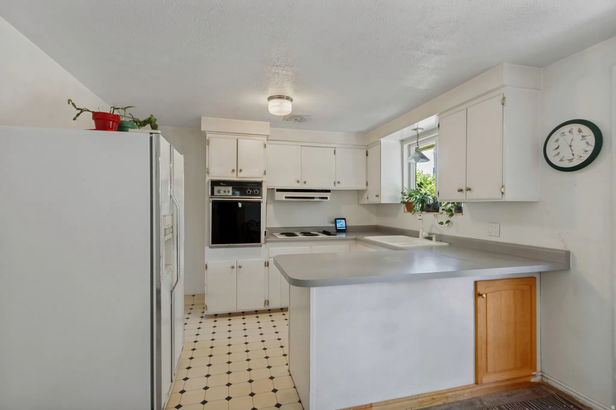 White cabinetry, built-in oven, countertop range, and checkered flooring