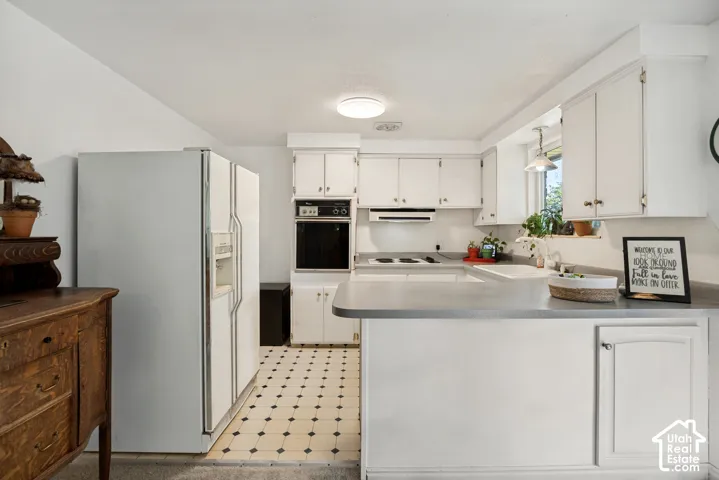 Kitchen featuring white cabinetry, built-in oven, range cooktop, recessed lighting, and patterned flooring