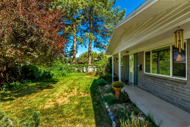 Front exterior featuring a covered porch, brick facade, and mature landscaping
