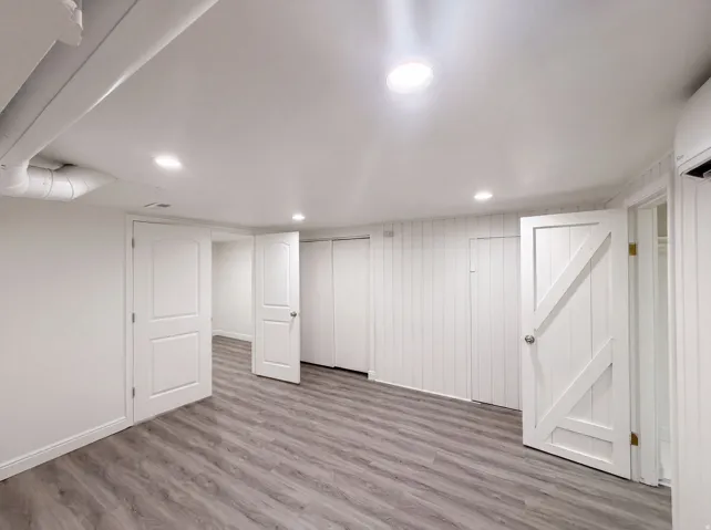 Recessed lighting, wood-finish flooring, white paneled walls, and white solid doors