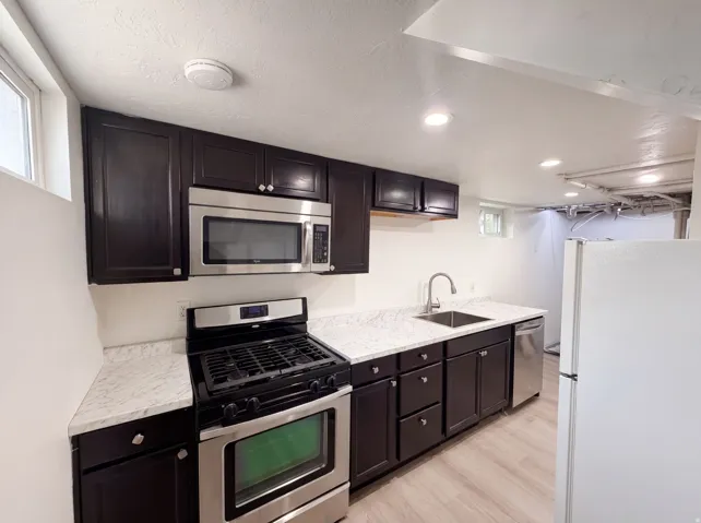 Dark wood-finish cabinetry with light countertops, stainless steel appliances, and wood-finish flooring