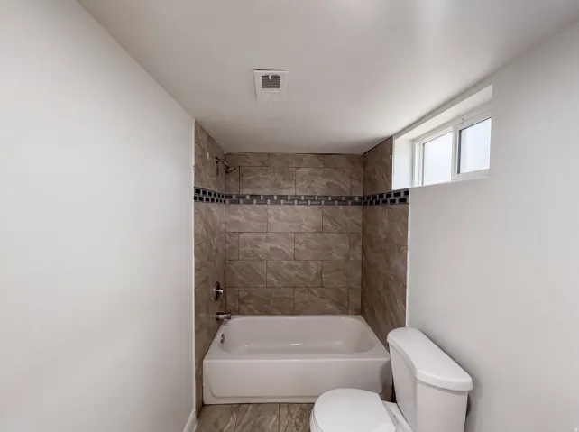 Tub and shower combination with tiled surround, mosaic accent band, and an integrated window