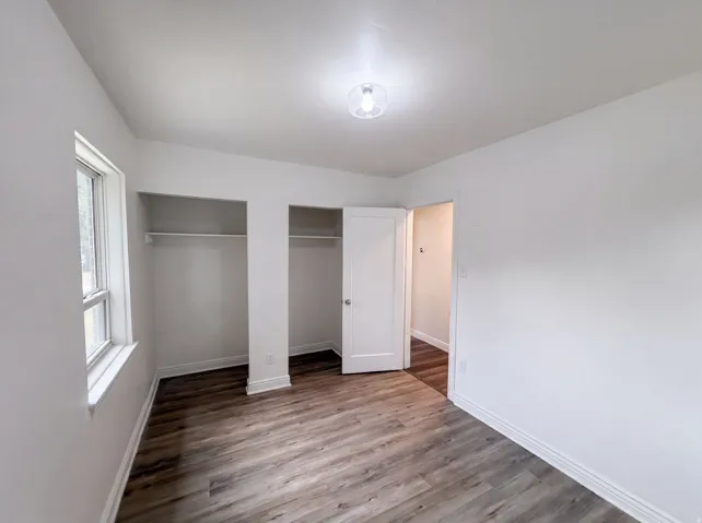 Wood-finish flooring, white walls, and a contemporary ceiling light fixture