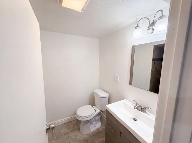 Vanity with integrated sink, brushed nickel faucet, wall-mounted mirror, and overhead light fixture