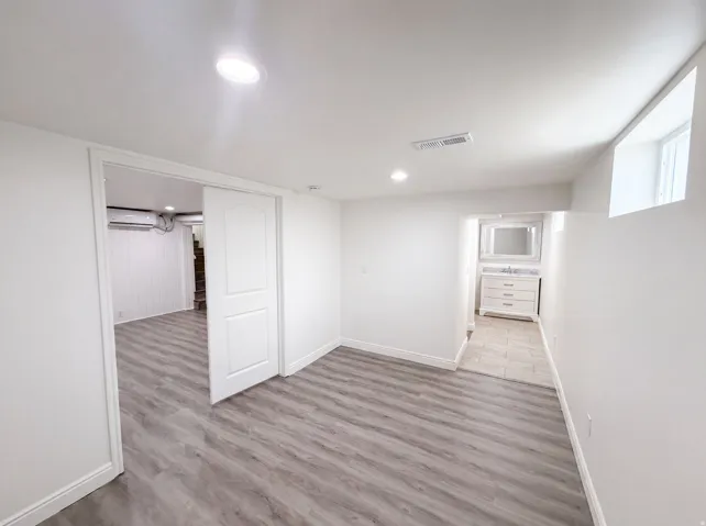 Wood-finish flooring with recessed lighting, white walls, and a sliding pocket door