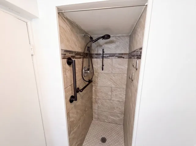 Walk-in shower with tiled walls and a mosaic accent band