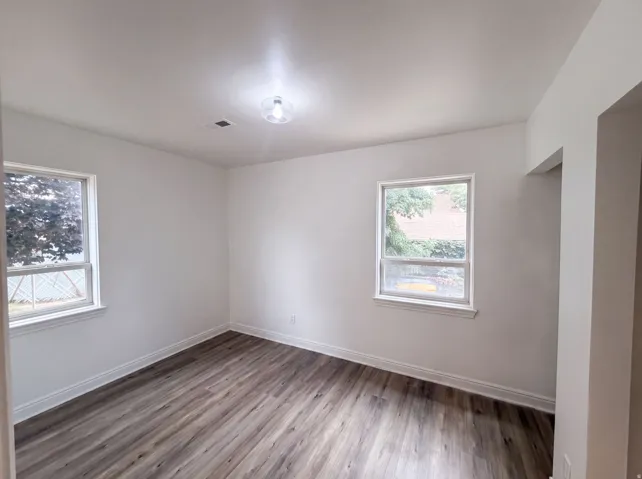 Bright interior with two windows, wood-finish flooring, and a ceiling-mounted light fixture