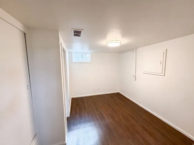 Hardwood-finish flooring, white walls, and a ceiling-mounted light fixture