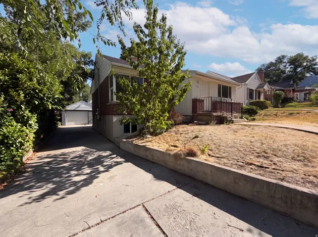 Brick and siding exterior with concrete driveway leading to a detached garage