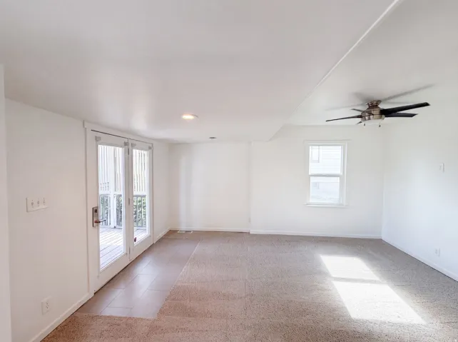 Recessed lighting, ceiling fan, white paneled walls, and double glass doors