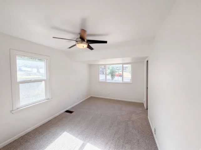 Wall-to-wall carpeting, white painted walls, and a ceiling fan with integrated lighting