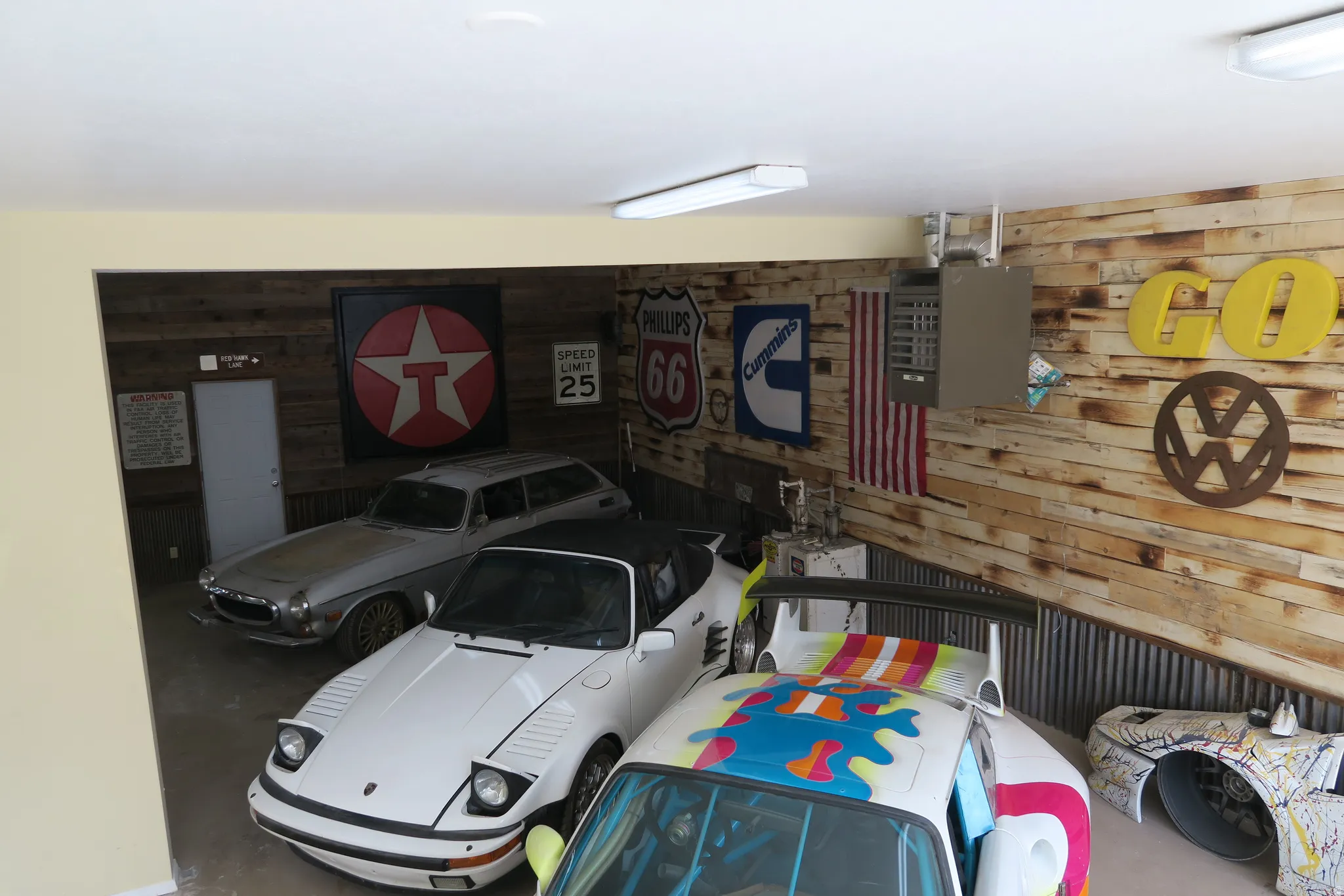 Garage space featuring wood-paneled walls, corrugated metal wainscoting, and fluorescent lighting fixtures