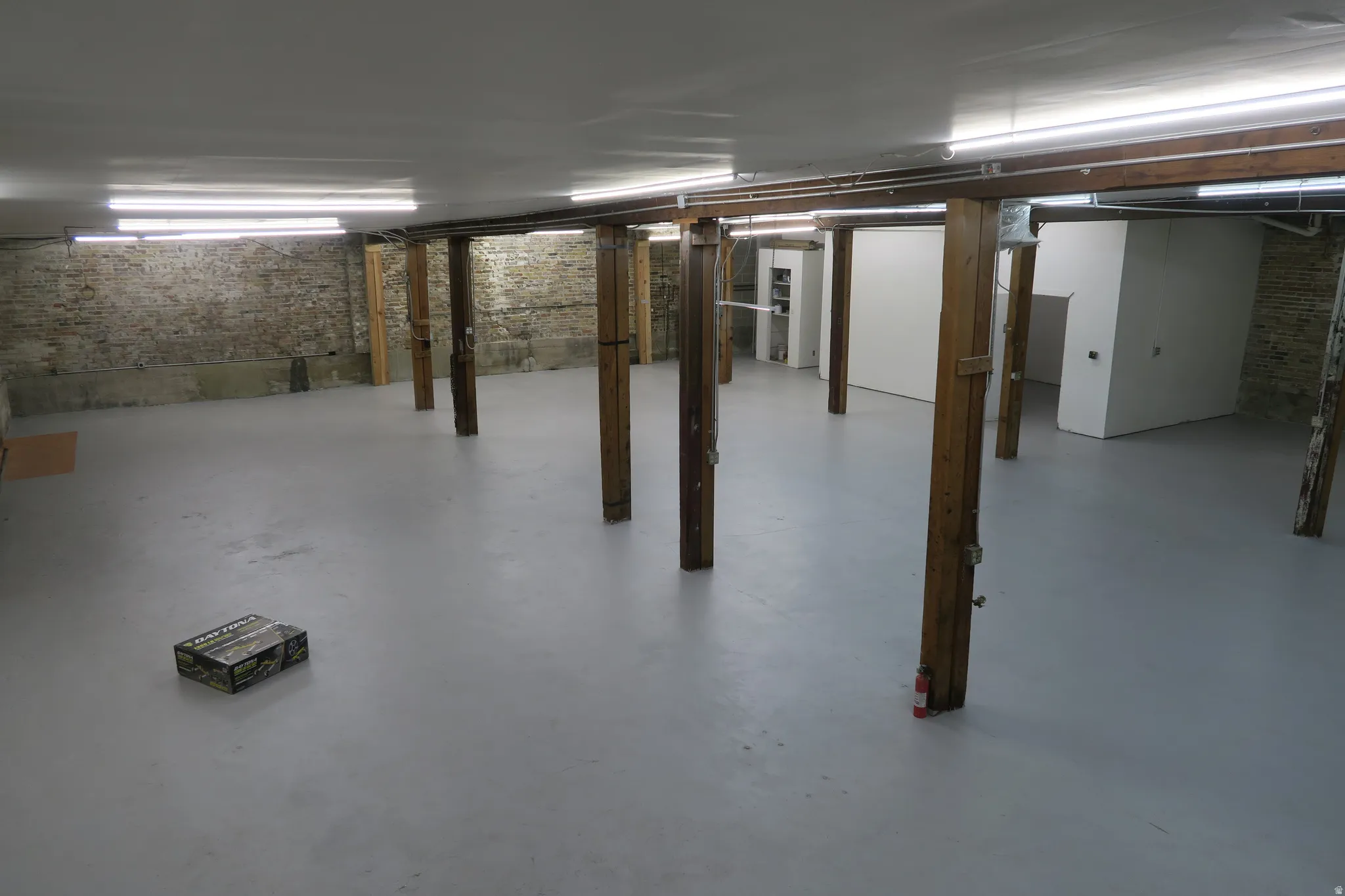 Expansive lower level with concrete flooring, exposed brick walls, and structural wood columns