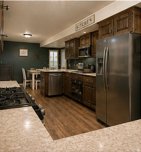 Kitchen featuring wood-finish cabinetry, stainless steel appliances, a center island with a built-in dishwasher, and wood-finish flooring