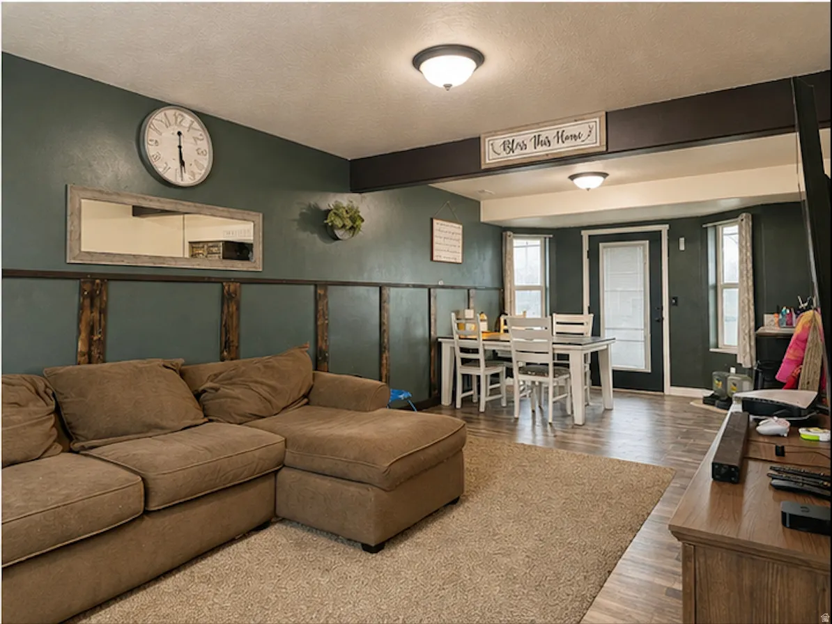 Open-concept living area with wood-finish flooring, a dining space, and multiple windows